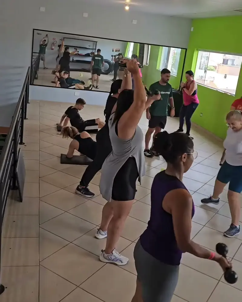 Turma de aula funcional levantando halteres no salão de paredes verdes