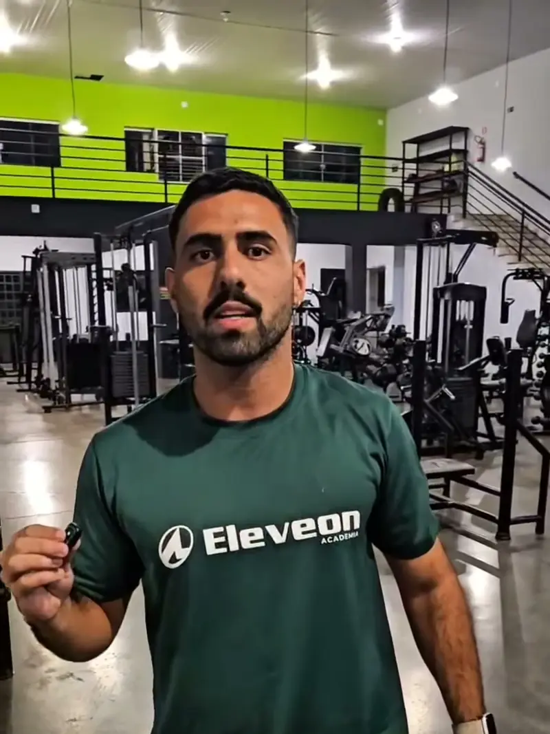 Professor da Eleveon explicando a aula de alongamento, diante da parede verde-limão