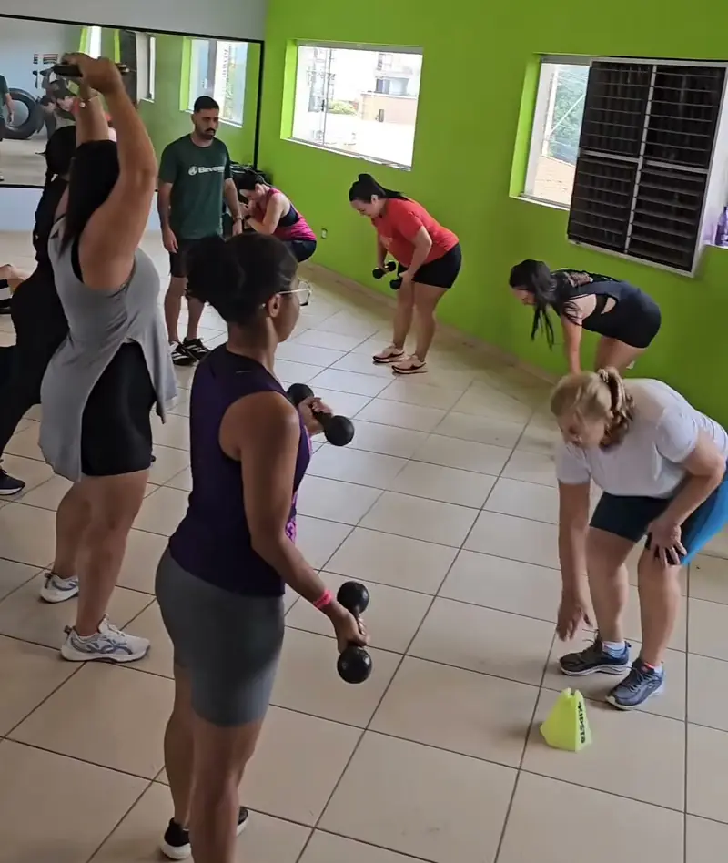 Turma de aula funcional com halteres, no salão da academia